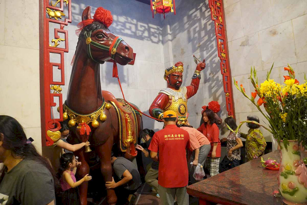 People crawl through the belly of the Red Hare horse statue to seek good fortune
